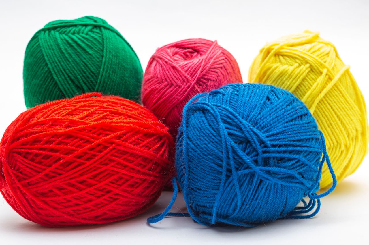 A vibrant collection of red, green, blue, yellow, and pink yarn balls arranged closely for crafting inspiration.